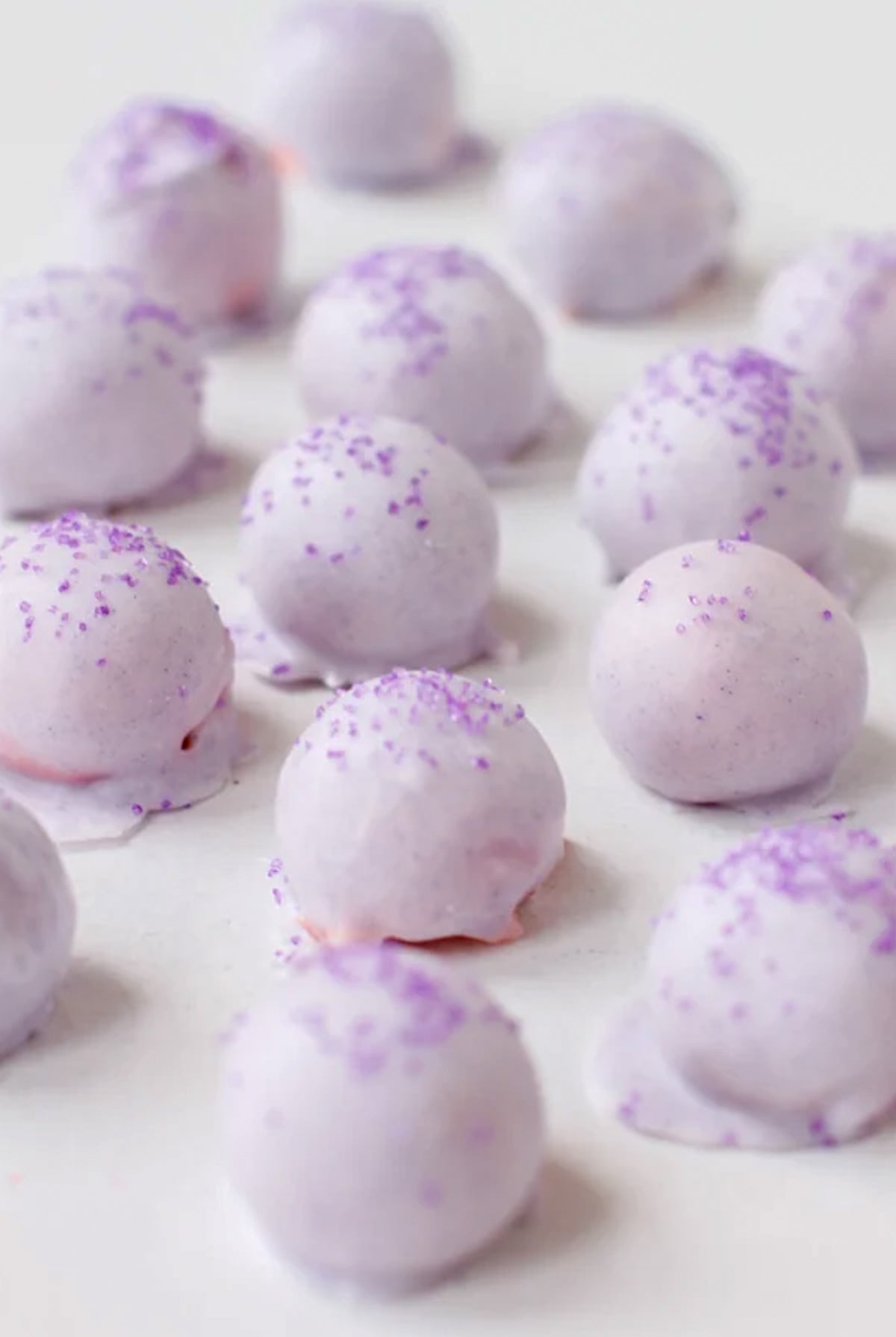 pastel purple cake balls all lined up on a white surface