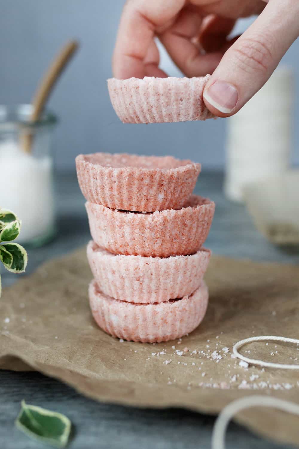 woman's hand stacking flat, pink bath bombs on top of each other