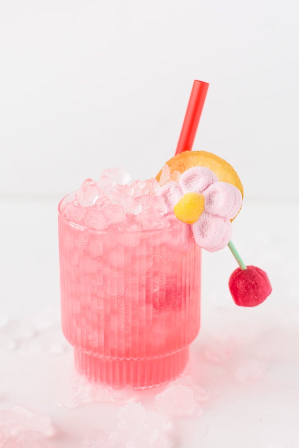 pink cocktail in short ribbed glassware with candy garnish and red straw