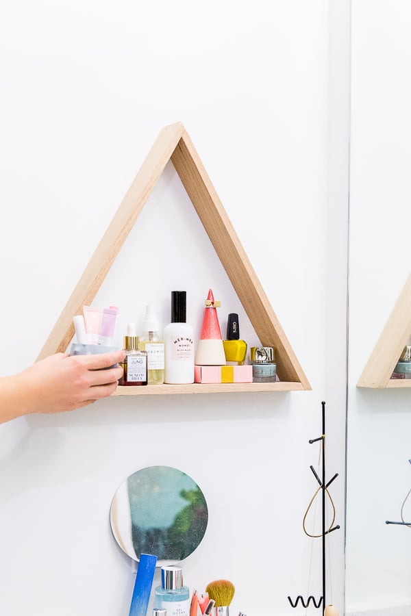 Use a uniquely shaped shelf to store everyday items. Click through for the full reveal of this minimal modern bathroom makeover.