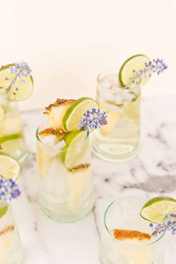 A tropical cocktail recipe for pineapple lime sangria spritzers. Love the edible flower garnish.