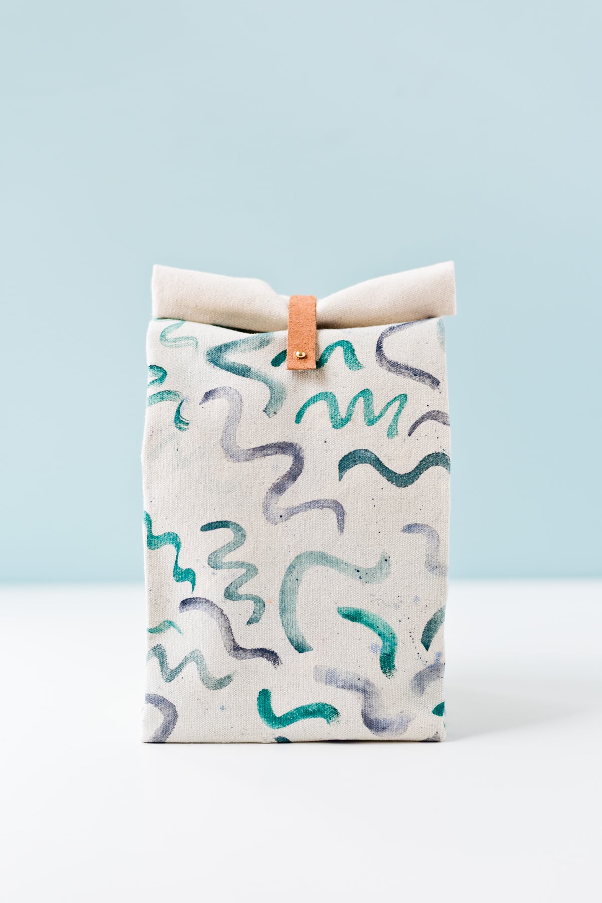canvas lunch bag with handprinted squiggle designs and blue background