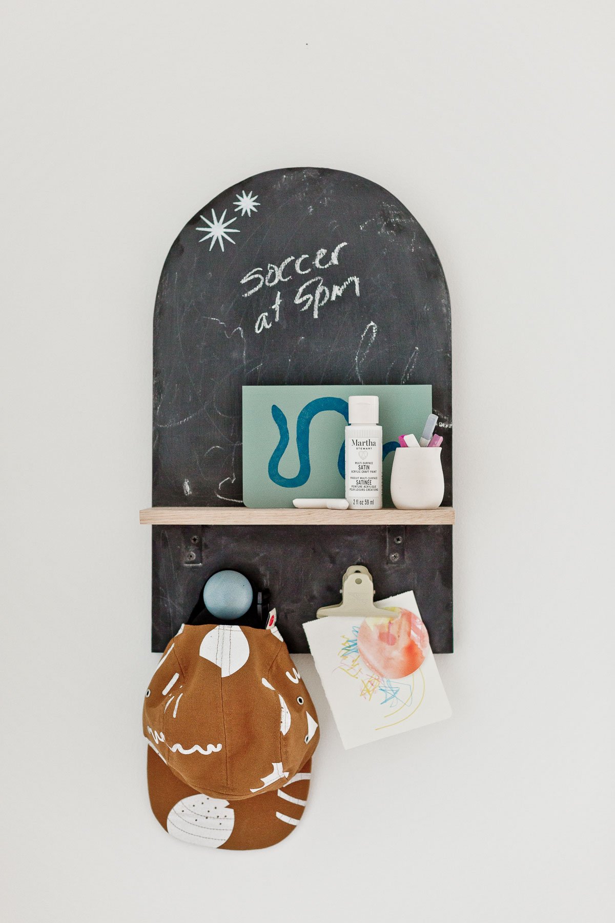 arch shaped chalkboard with hooks and a shelf