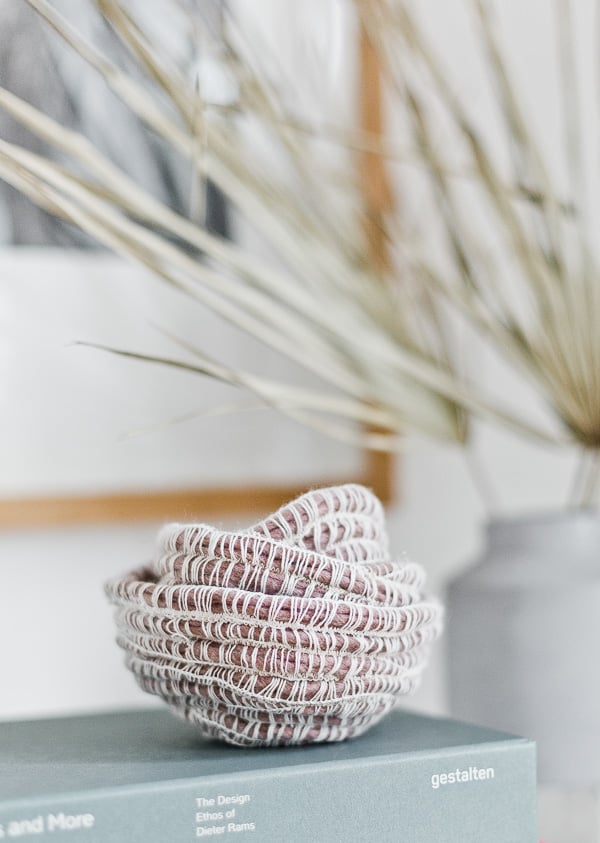 Simple yarn baskets in a mauve color, resting on a grayish blue book.