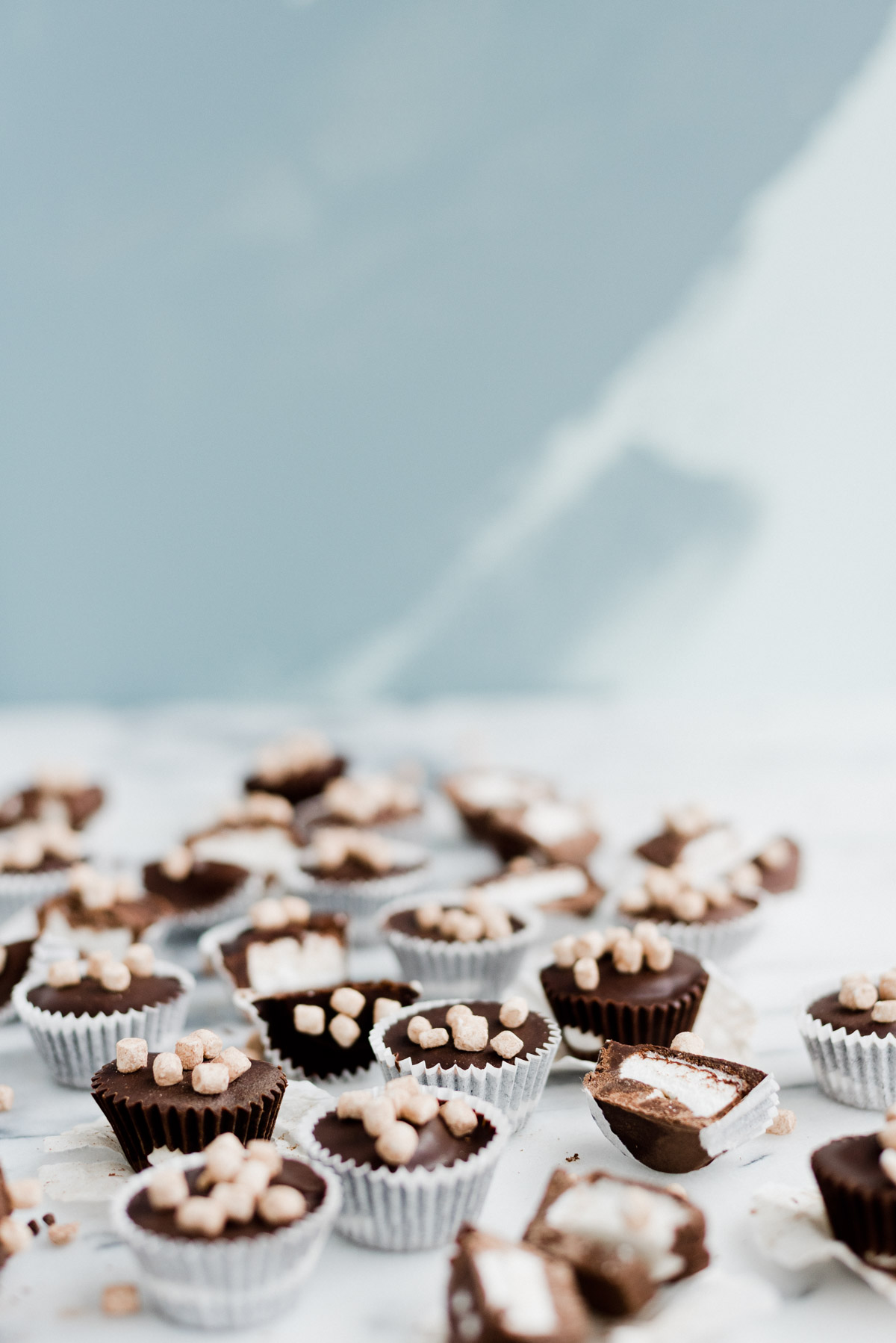 chocolate and marshmallow candy cups scattered on marble countertop