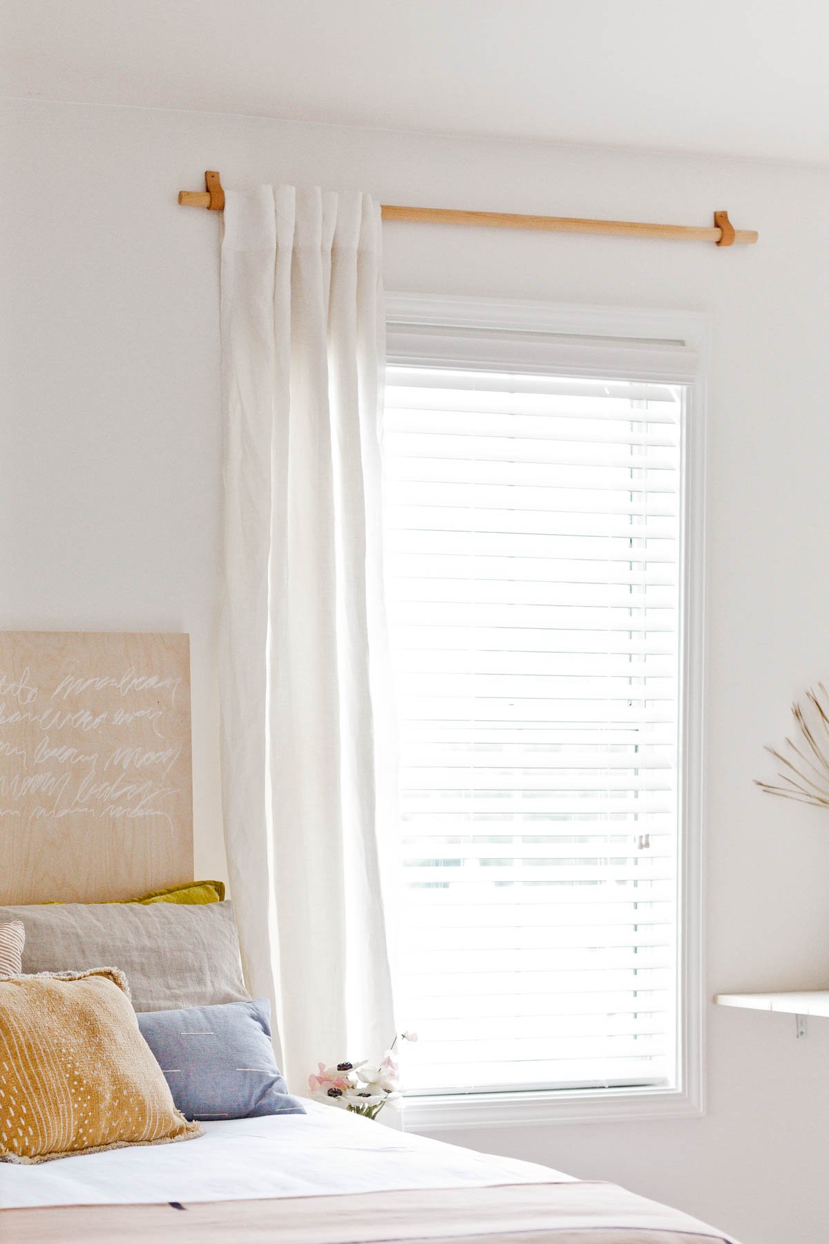 wood curtain rod with white linen curtain in a small organic modern bedroom for teen