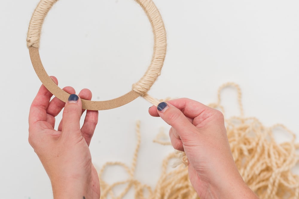 Wrapping yarn around a floral ring to make a fall wreath.