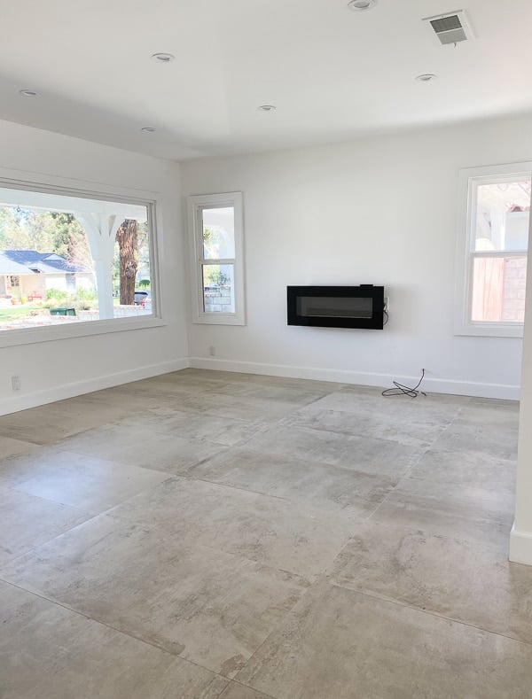 Empty living room (before photos) with concrete tile floors.
