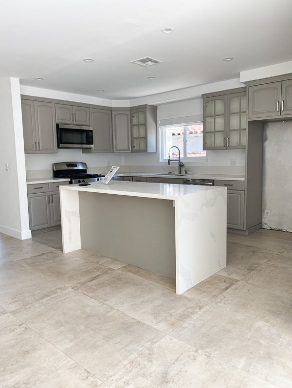 Before photo of grey cabinet kitchen, with white countertops.