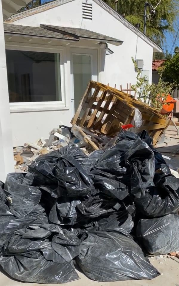 Before photos of construction with piles of garbage bags in backyard.