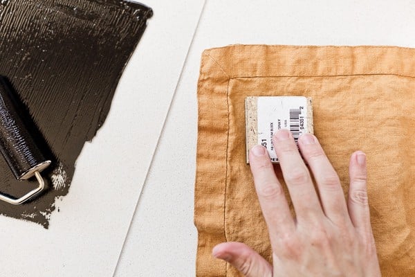 Pressing carving linoleum block onto fabric to create a permanent pattern.
