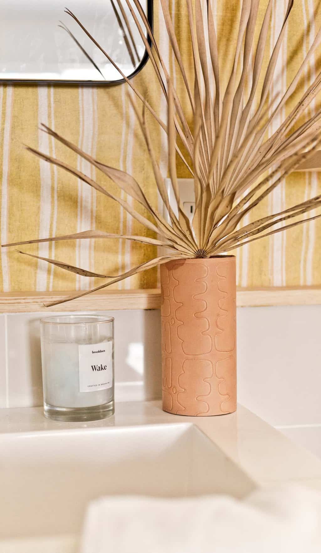 Embossed leather vase with funky pattern in a striped, colorful bathroom.