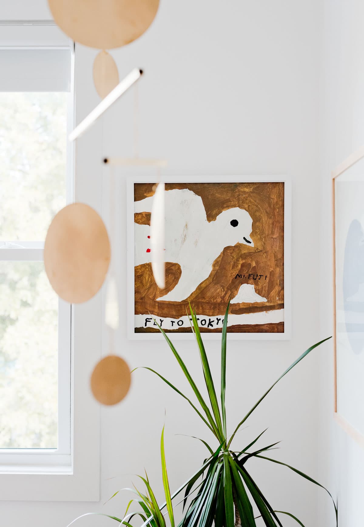 Painting of a bird that says 'fly to Tokyo', hanging in a child's nursery.