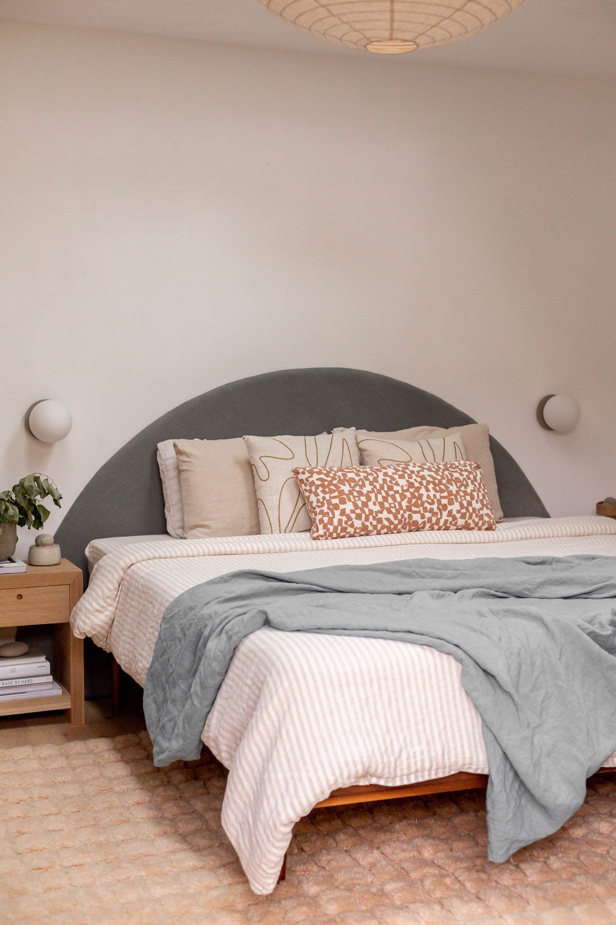 minimal modern bedroom with earthy neutral decor and round headboard 