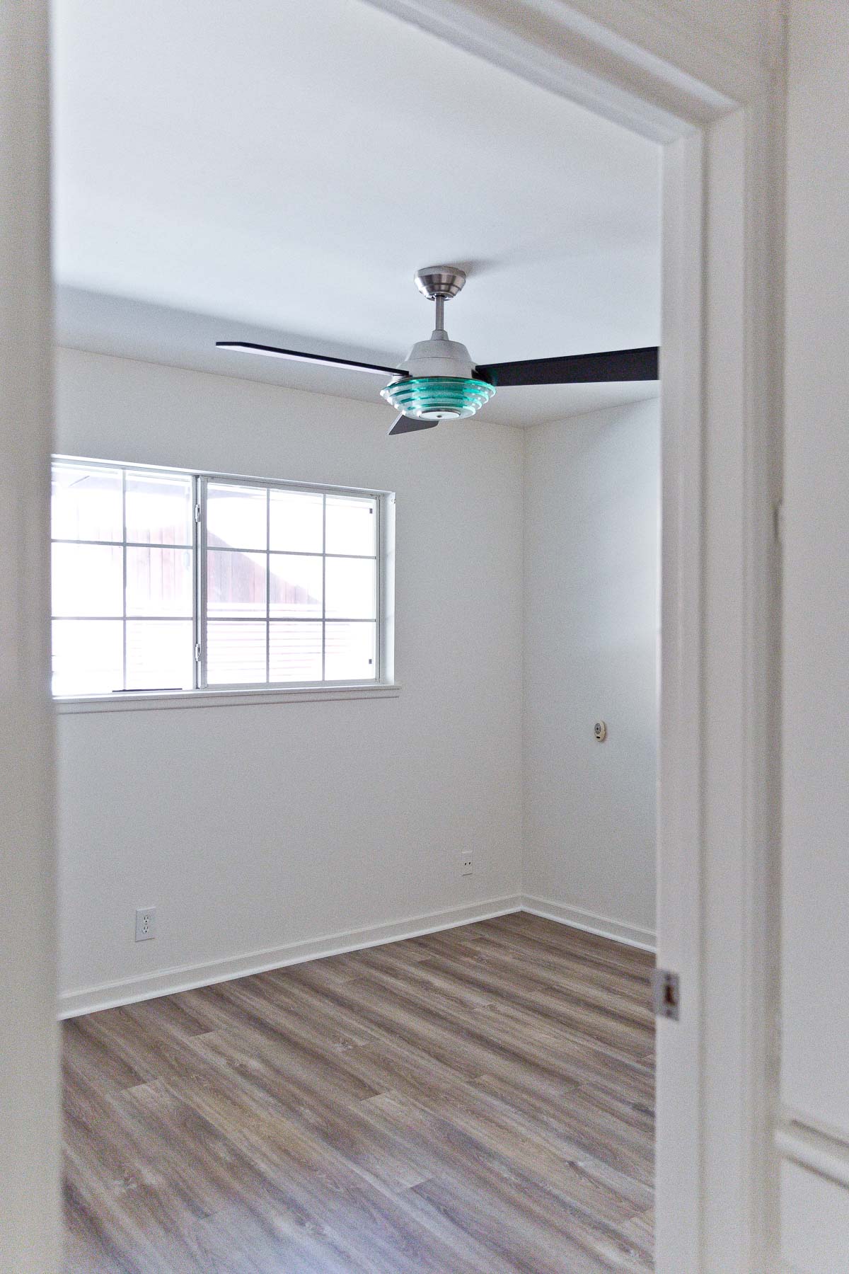 Photo of small, empty bedroom with ceiling fan.