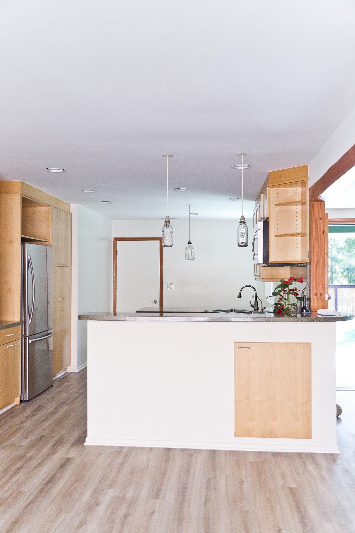 Image of empty kitchen with minimal wood cabinets and white walls.