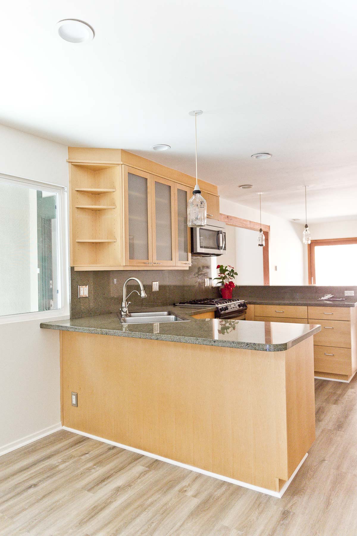 Image of empty kitchen with minimal wood cabinets and green natural stone counters.