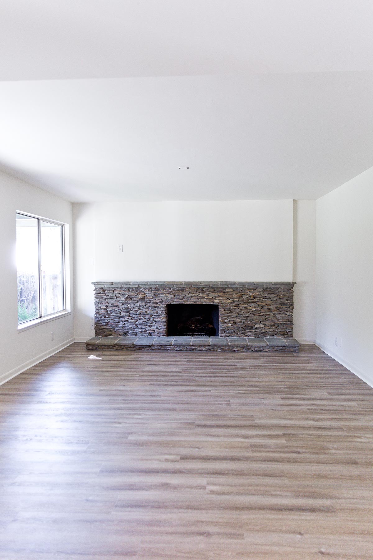 giant ledger rock fireplace in empty house with white walls