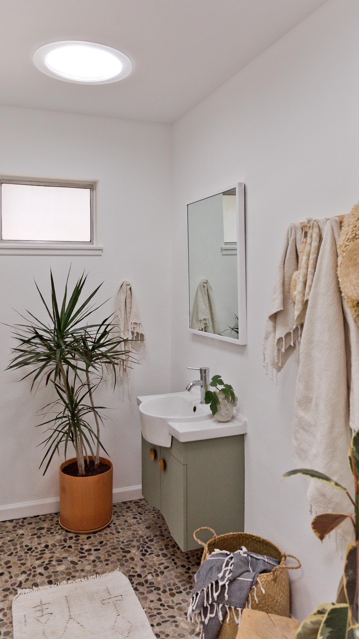 Organic modern bathroom with rock floors and olive green vanity