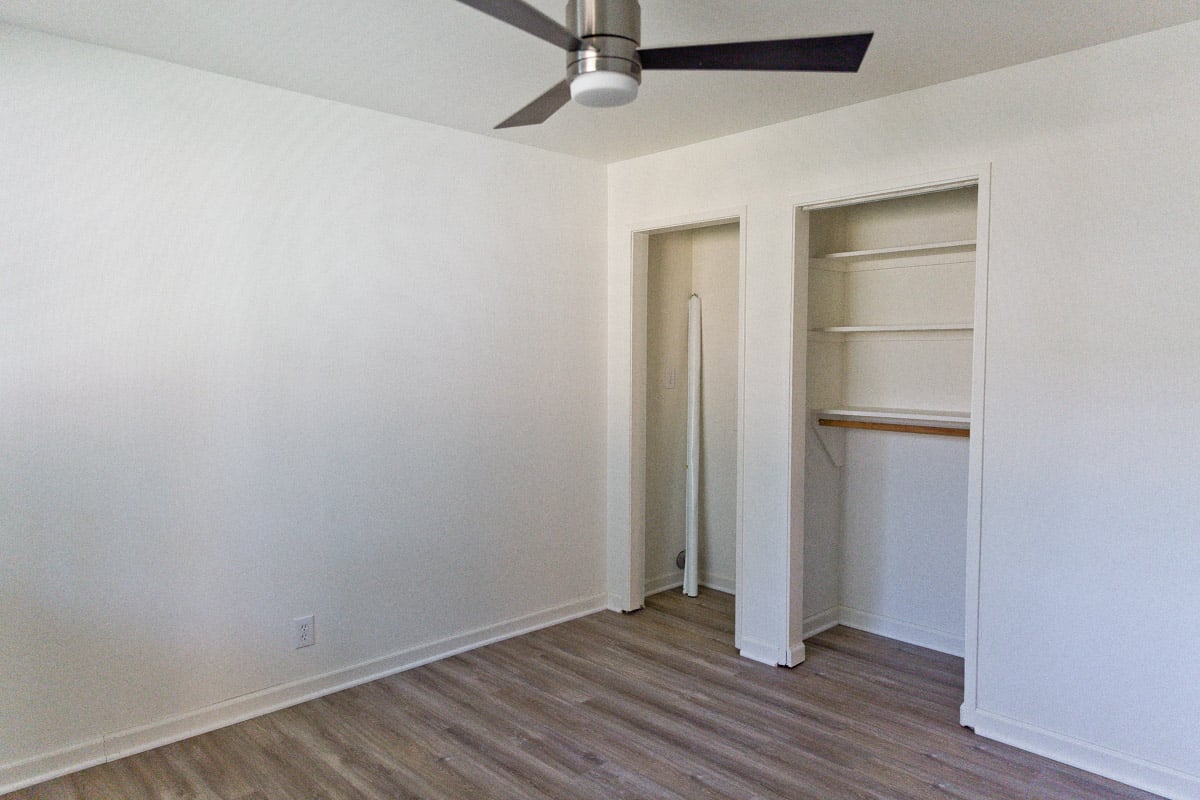 Empty room with two small closets and fan