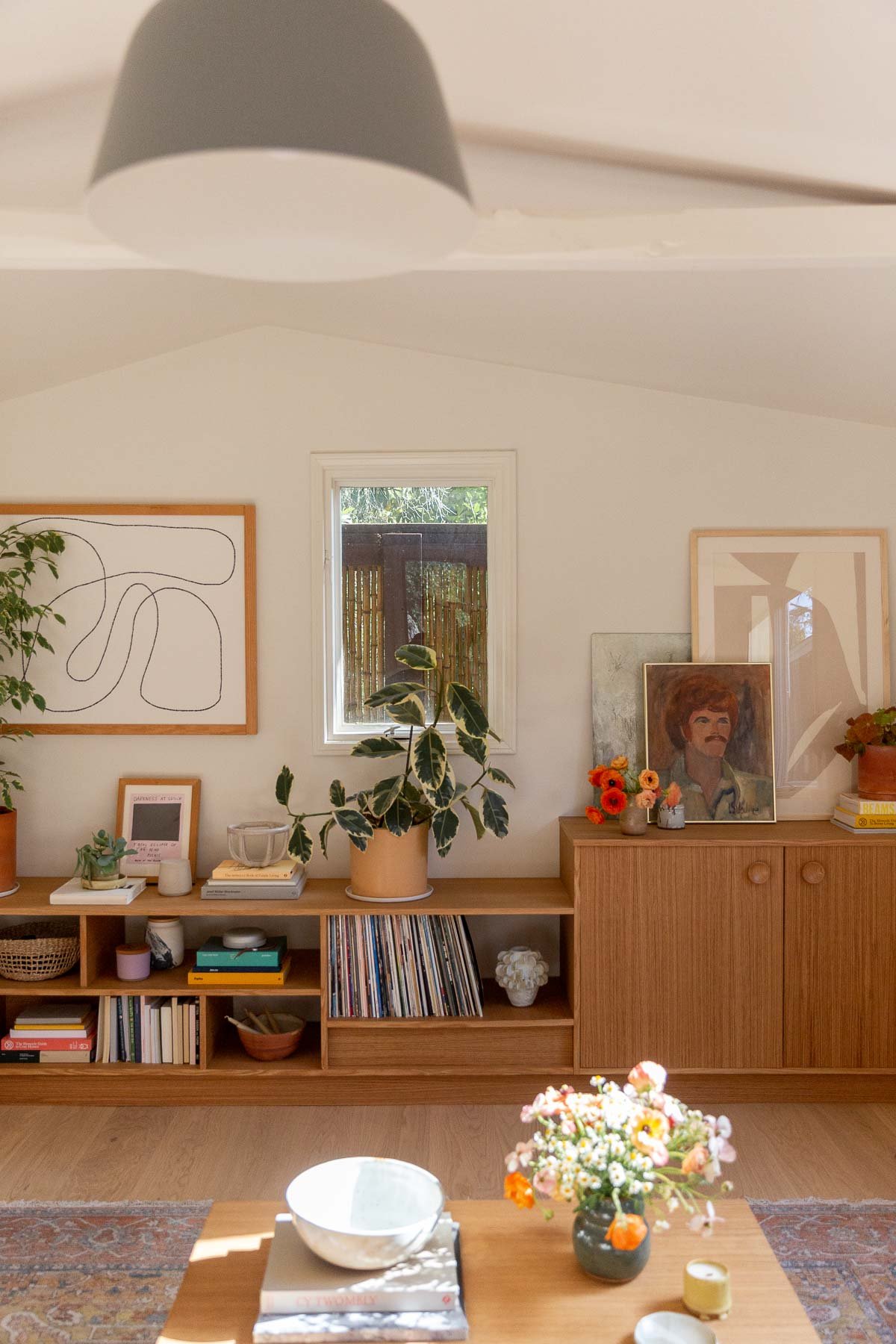 modern wood built in shelving unit in small room with vaulted ceilings and artwork
