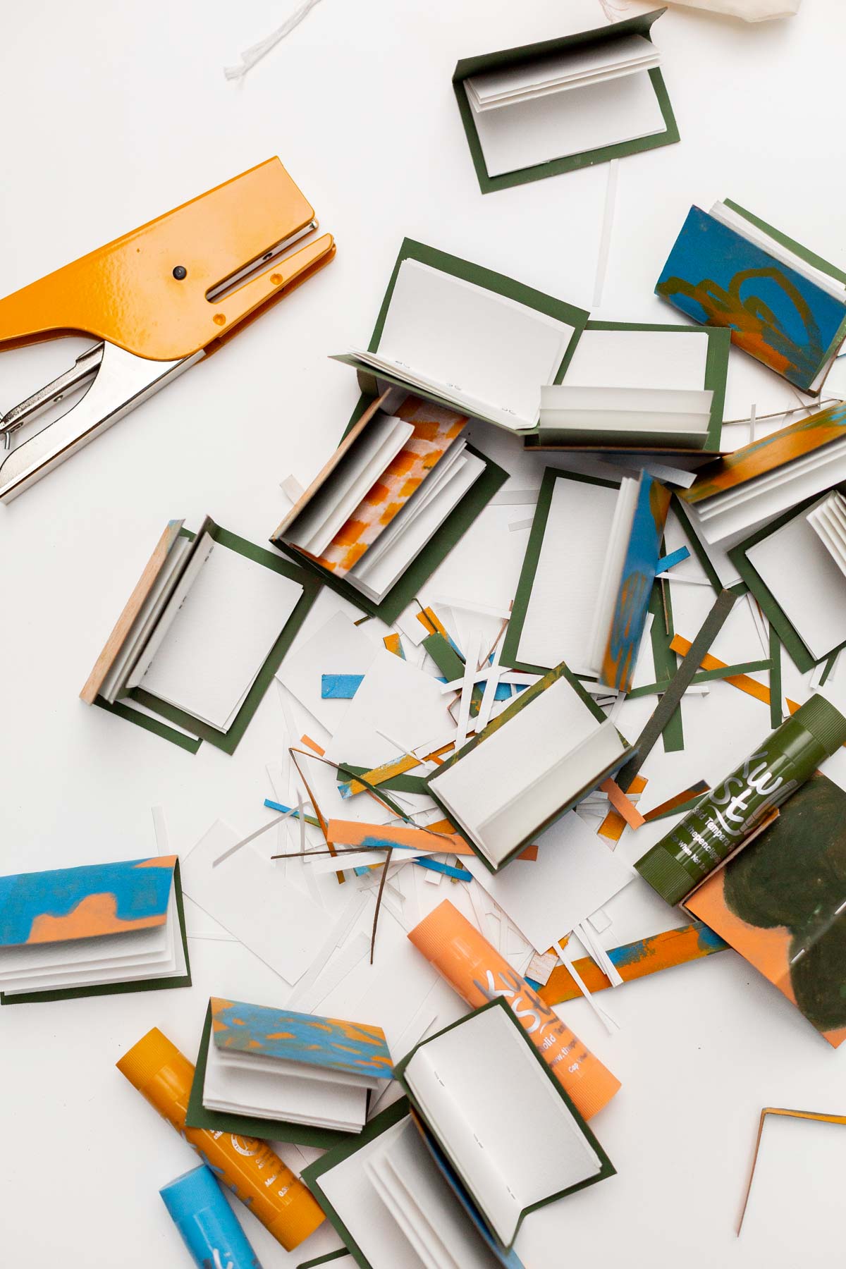 tiny notebooks being made with paper, paint, and a yellow stapler