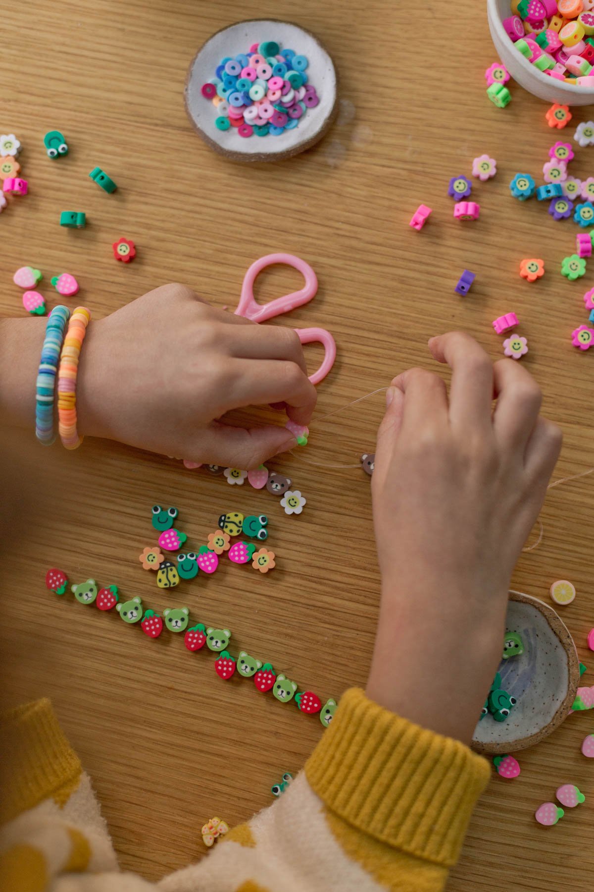 kid making small bracelets with polymer clay beads