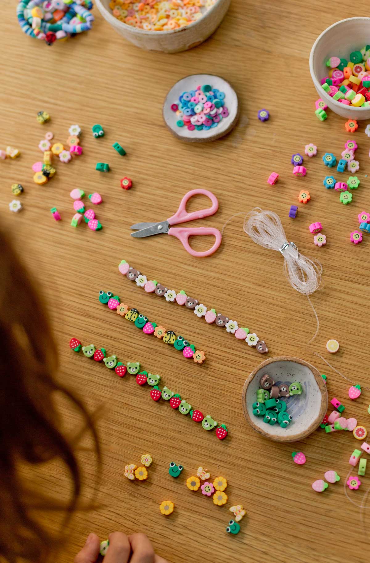 lining up clay bead bracelet designs with various shapes and colors of polymer clay beads