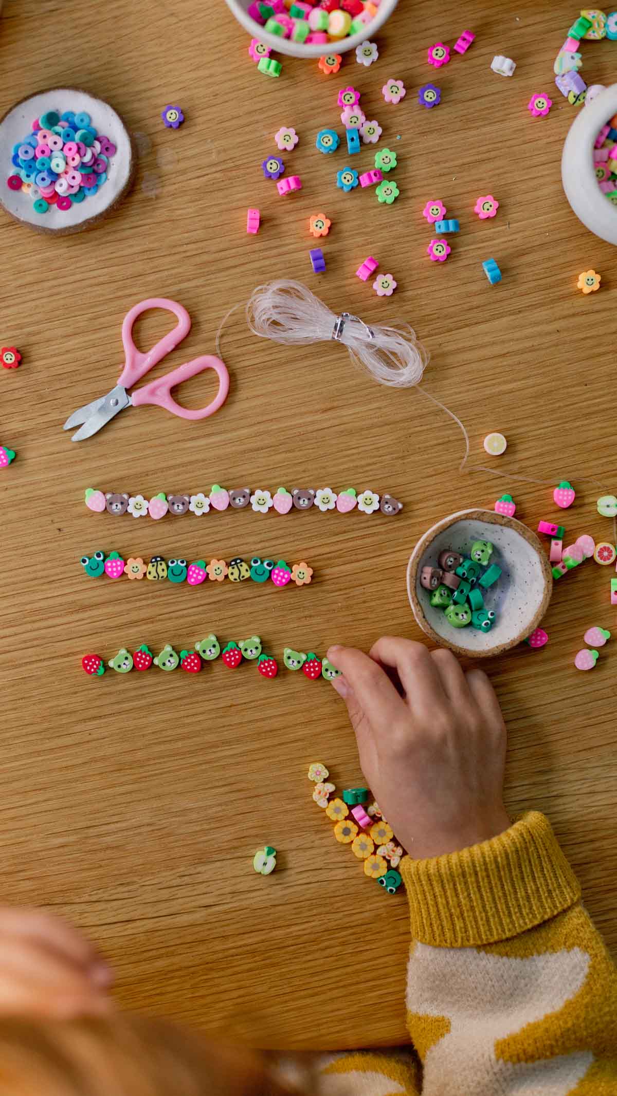 child designing beaded bracelets at a table surface