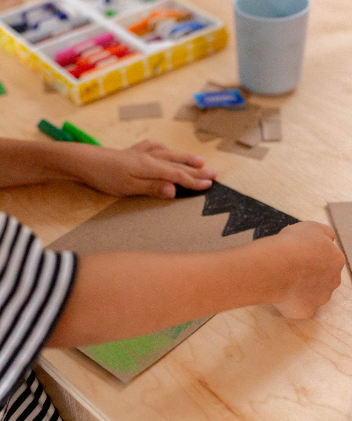 child crafting a halloween dry erase board with cardboard and crayons