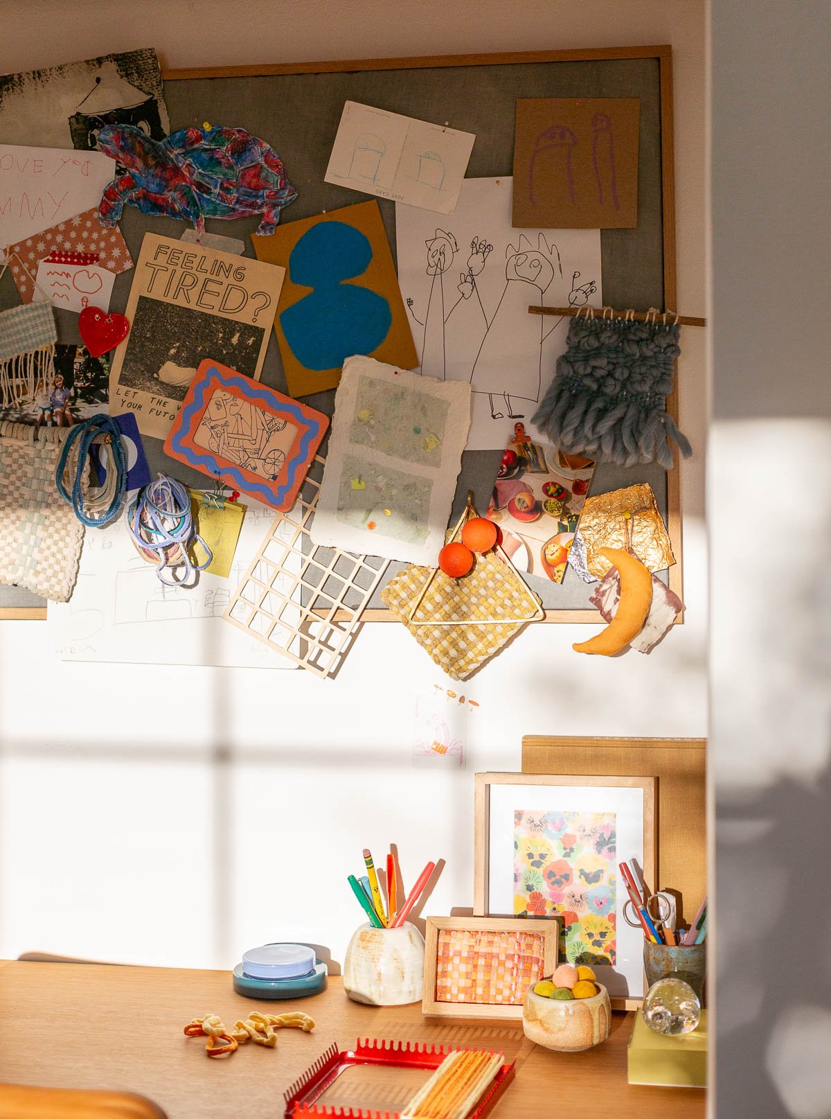 bulletin board over a desk filled with crafts, artwork, and doodles