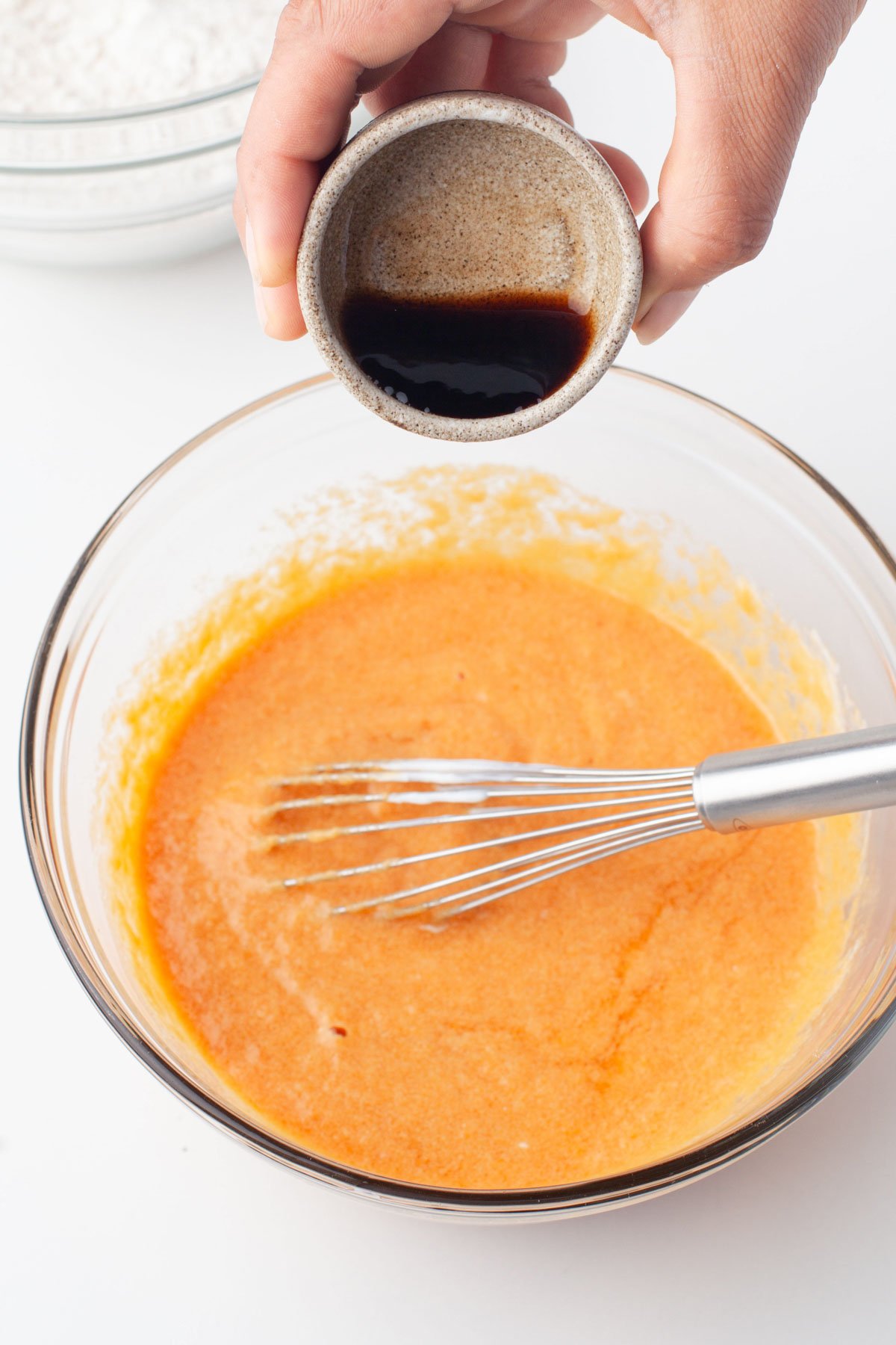 pouring vanilla into pumpkin cupcake mix in bowl