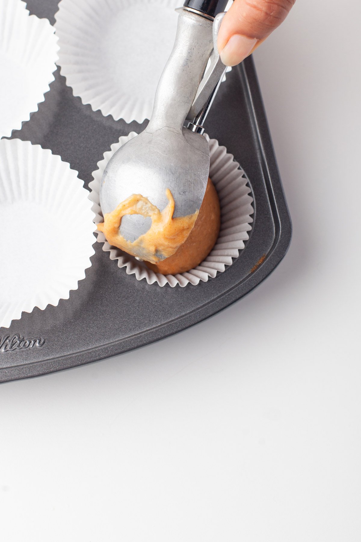 scooping pumpkin cake mixture into cupcake tins