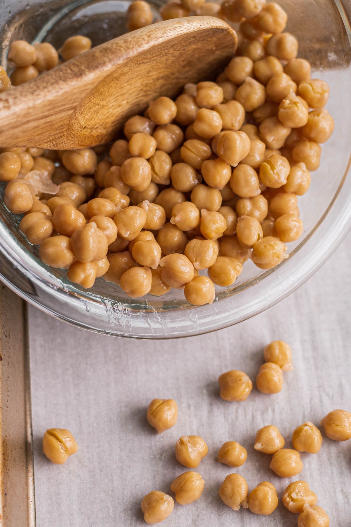 pouring chickpeas from a bowl onto a baking sheet to cook up and make crispy 