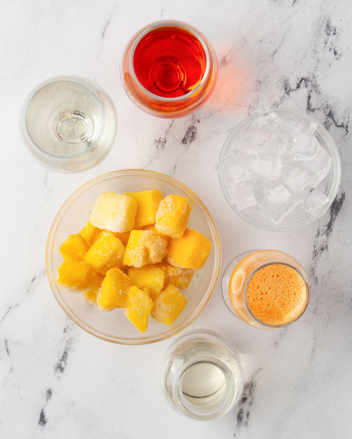 ingredients laid out on marble counter to make a frozen aperol spritz