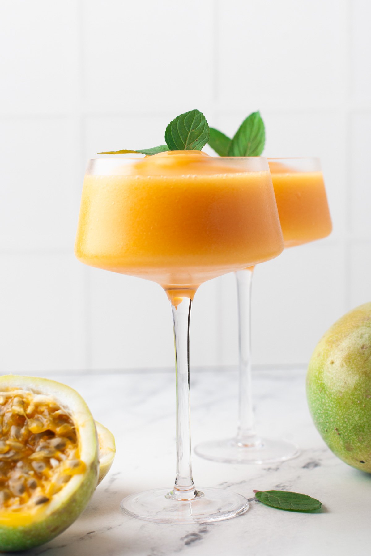 frozen cocktails that are orangish yellow in color with mint sprigs on top