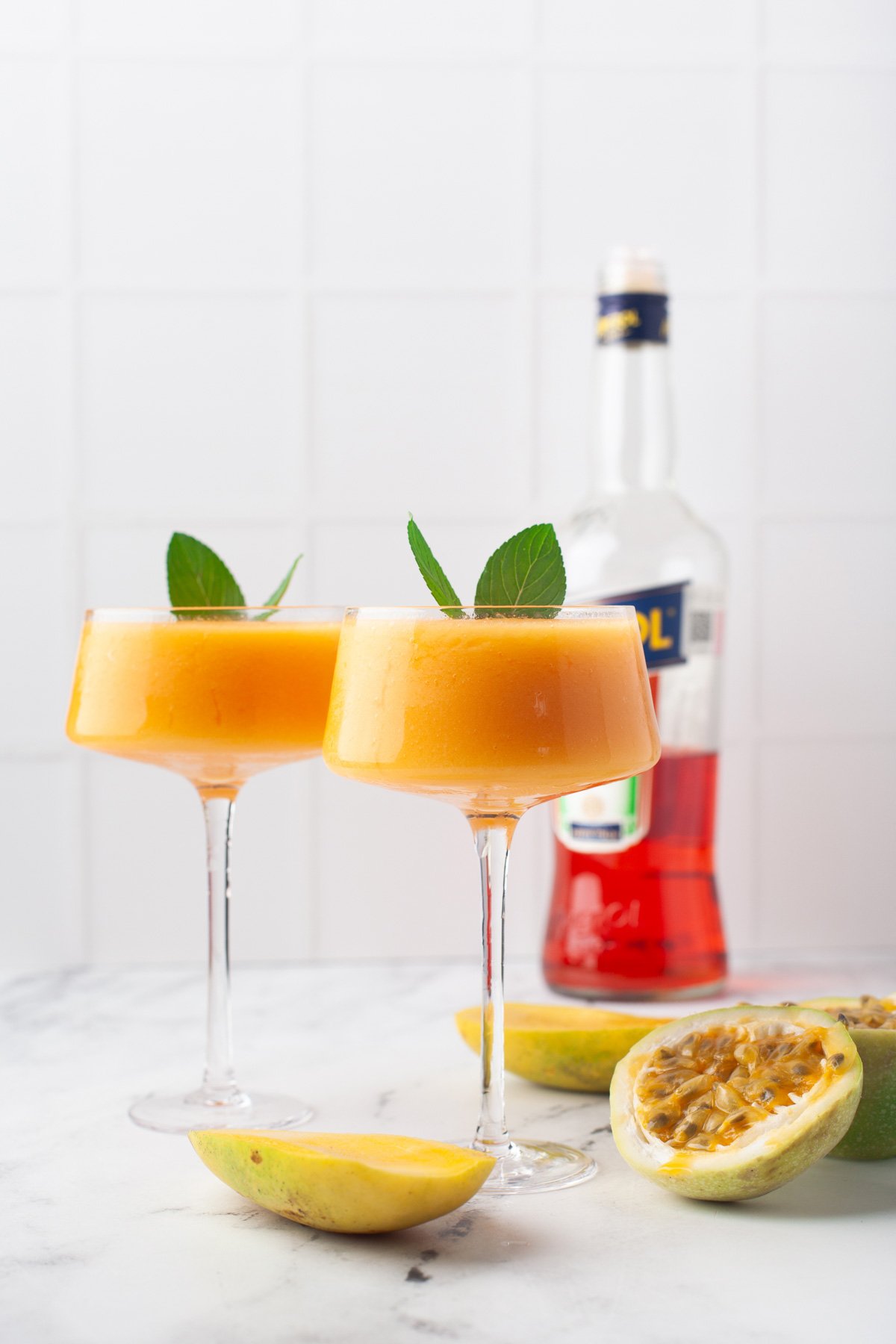 two frozen cocktails in vibrant colors, sitting on kitchen counter