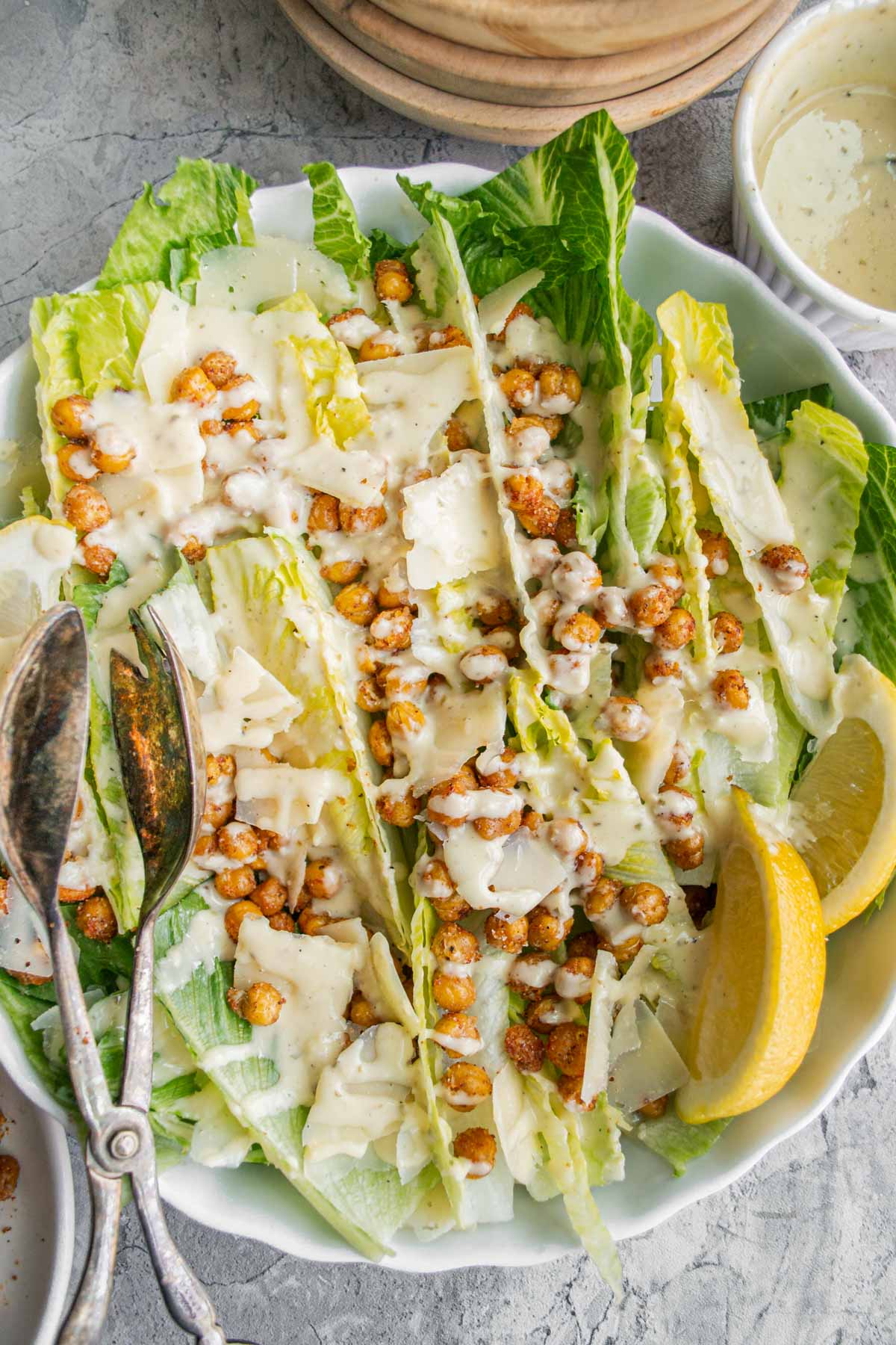 crispy chickpeas on top of a caesar salad with dressing and lemon slices