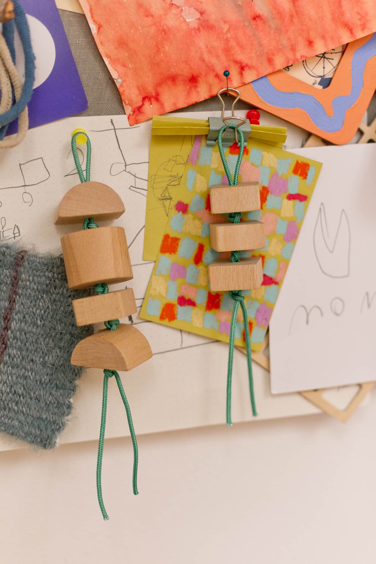 wood keychains hanging from a memo board with art behind it
