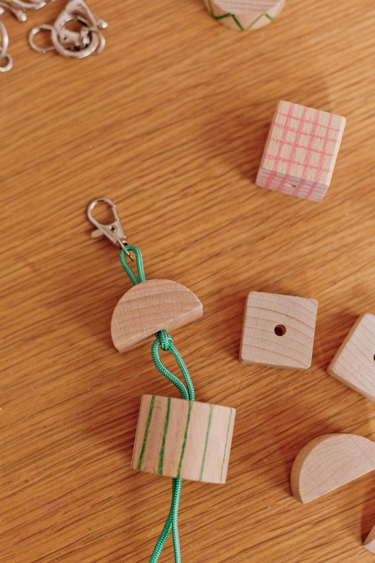 stringing wood blocks onto green cording with lobster clasp