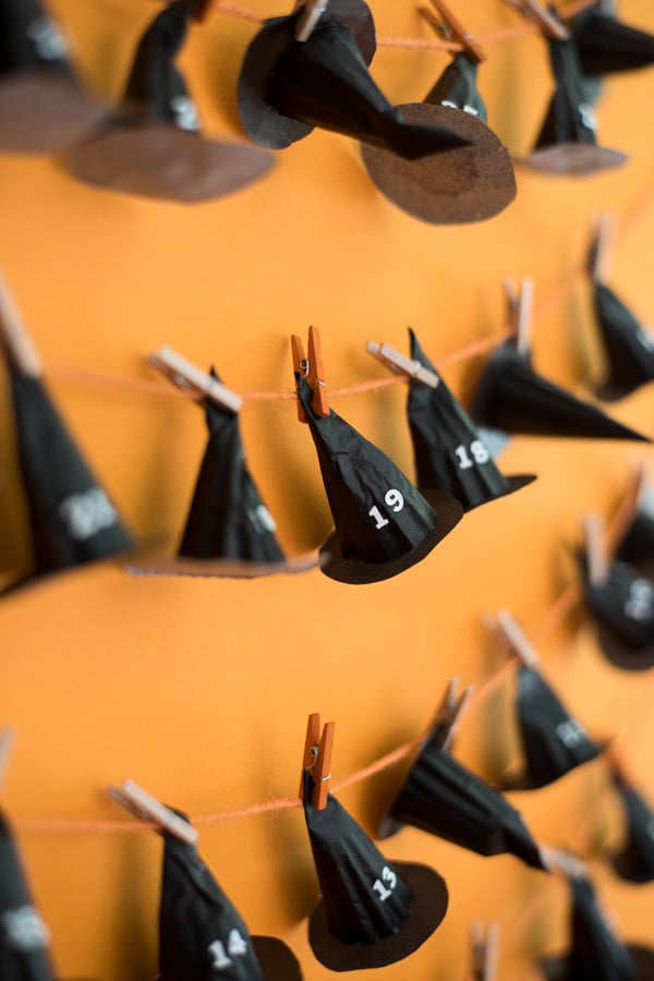 black hats lined up and numbered on a string for a calendar countdown with orange background