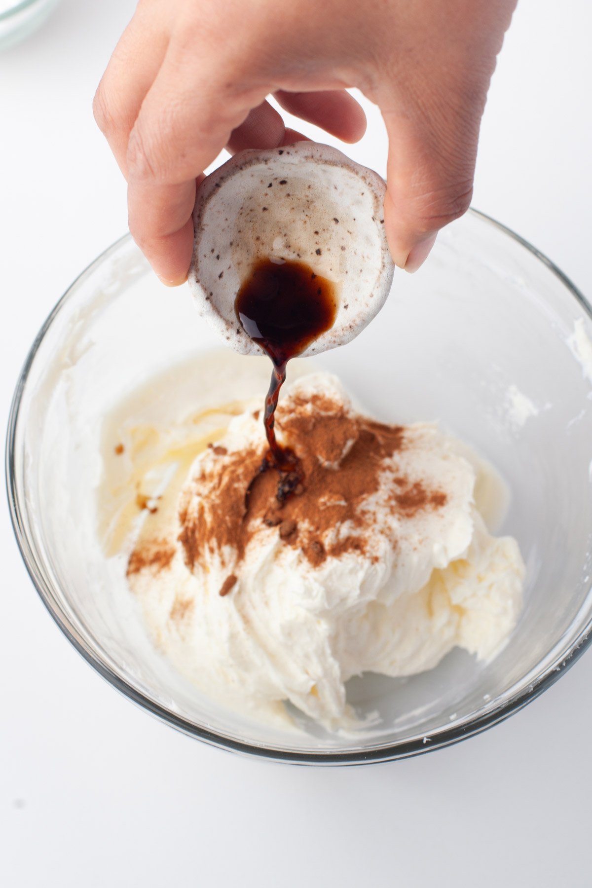 making cream cheese frosting and pouring ingredients into glass bowl