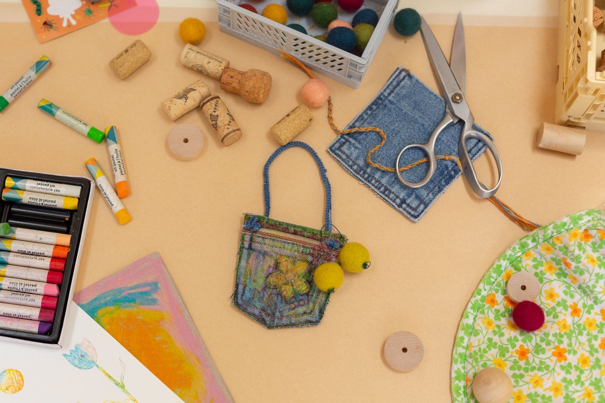 craft supplies laid out on table with homemade jean purse in the middle