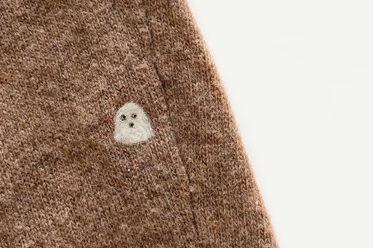 tiny felt ghost on brown sweater