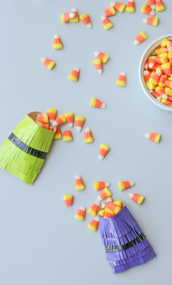 fringe party favor bags in green and purple with candy corn filling each one