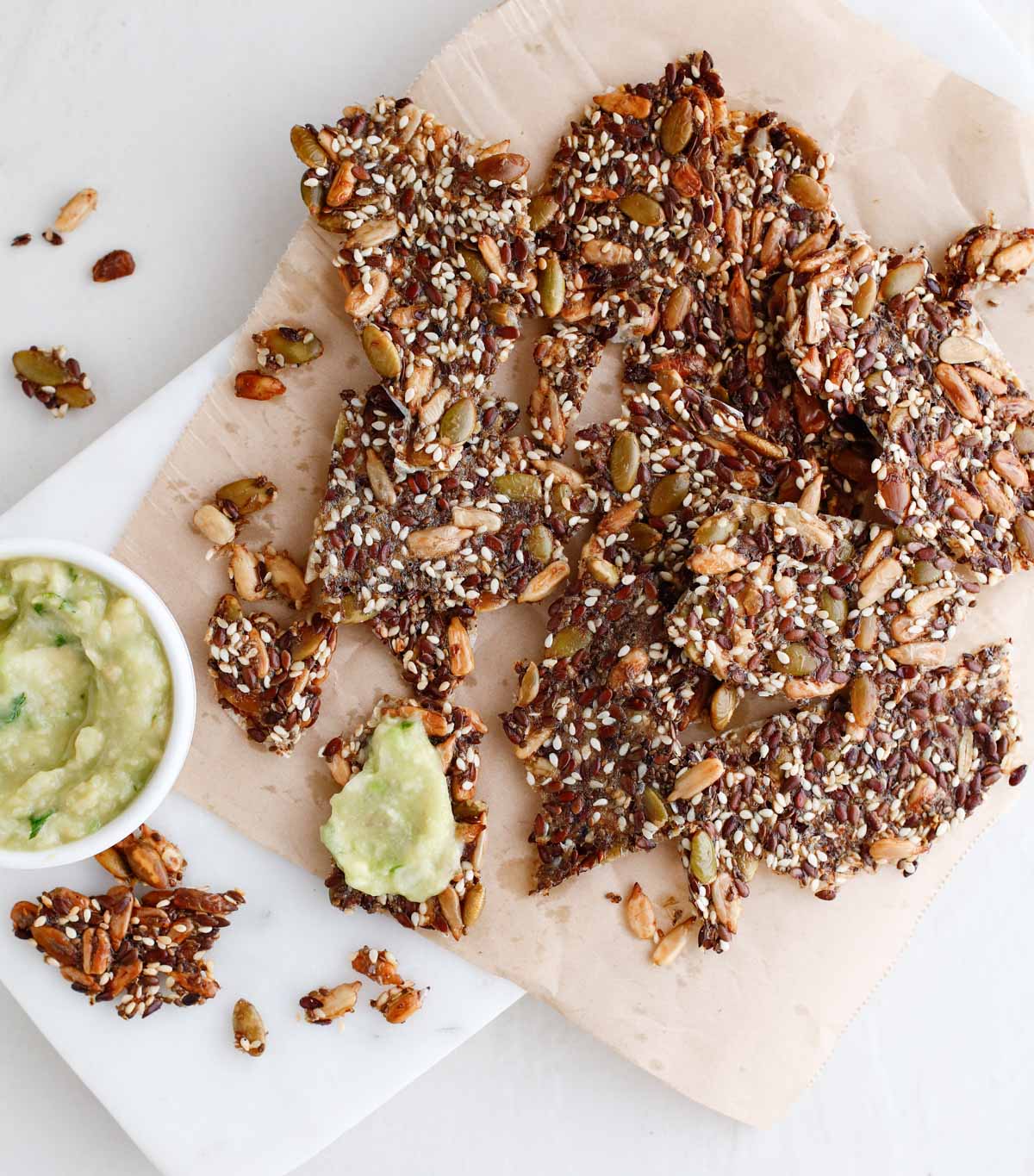 seed crackers on a marble board with avocado spread 