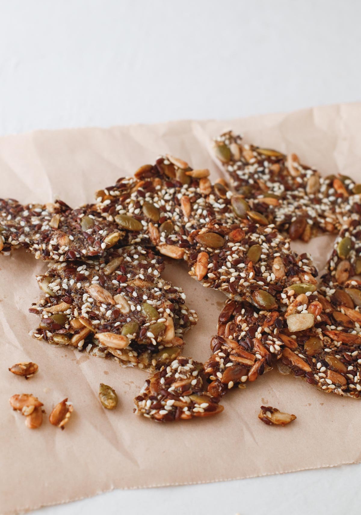 homemade seed crackers in small pieces on a counter with wax paper underneath