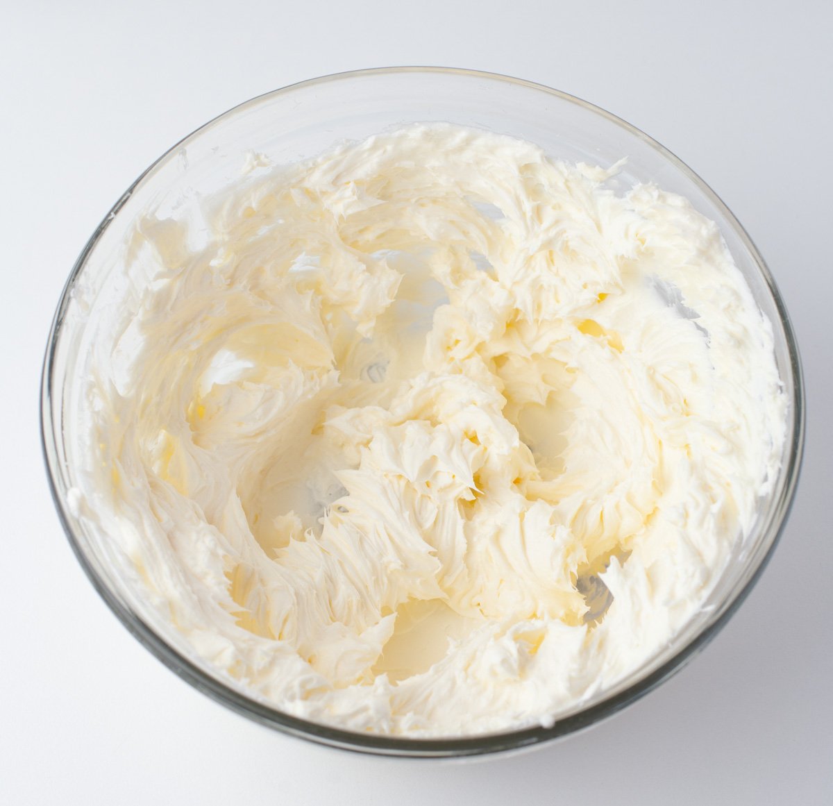 Blending crea, cheese frosting in glass bowl
