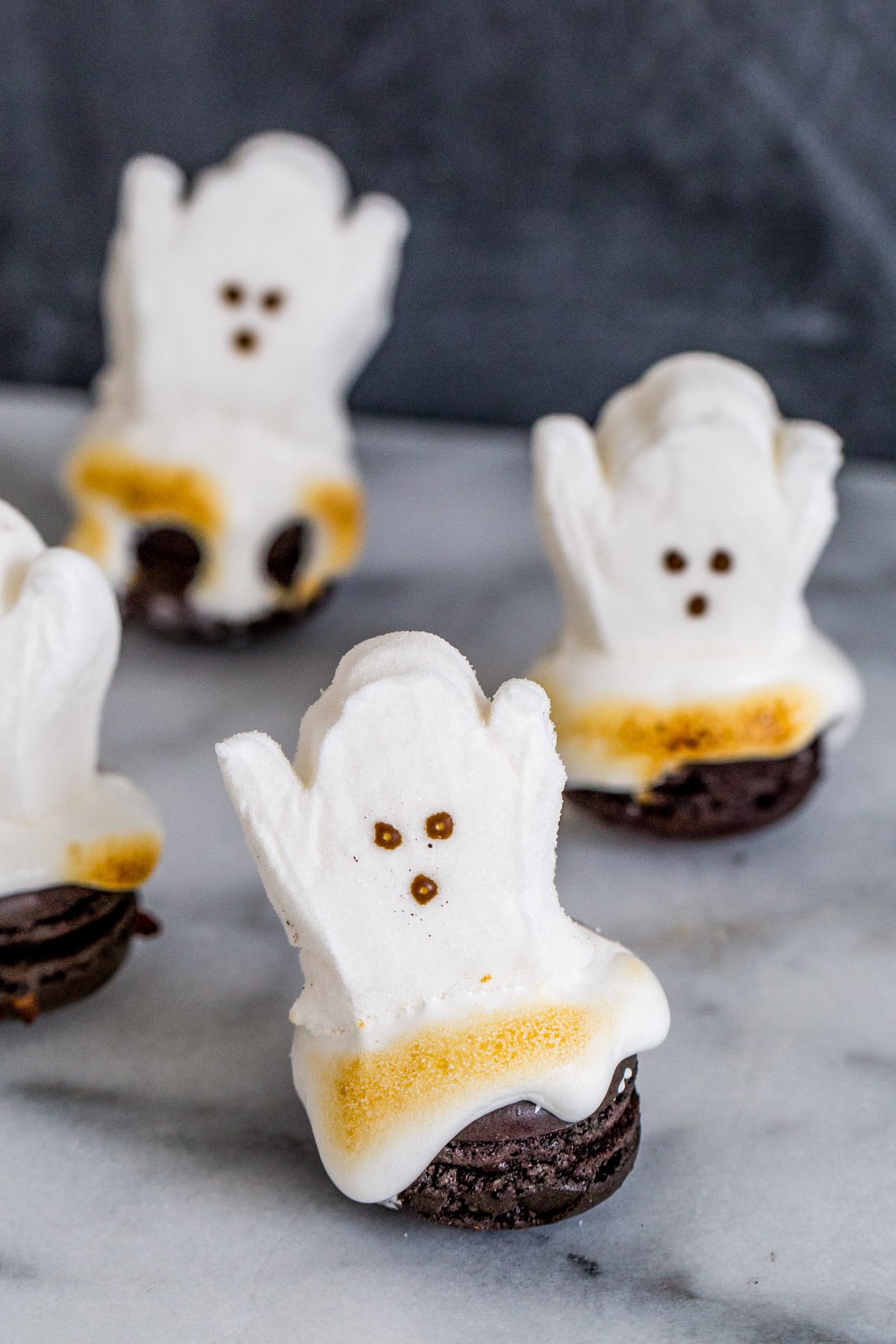 toasted marshmallows shaped like ghosts on top of chocolate macarons