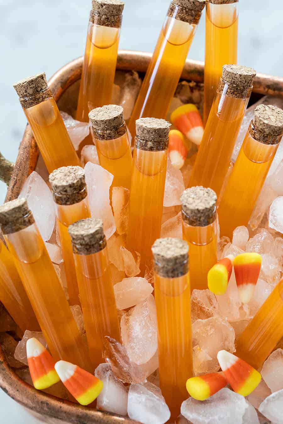 halloween cocktails in an ice tub with candy corns all around it